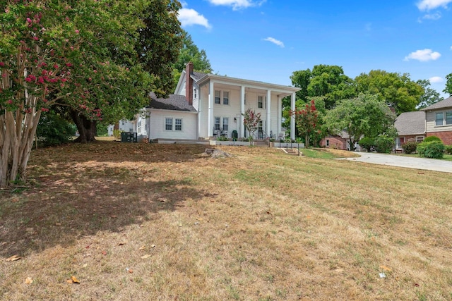 greek revival inspired property with a front lawn and covered porch