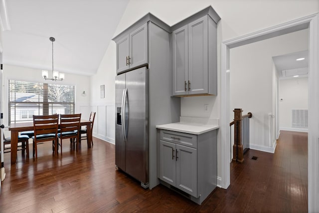 kitchen featuring gray cabinetry, stainless steel fridge, dark hardwood / wood-style flooring, and hanging light fixtures