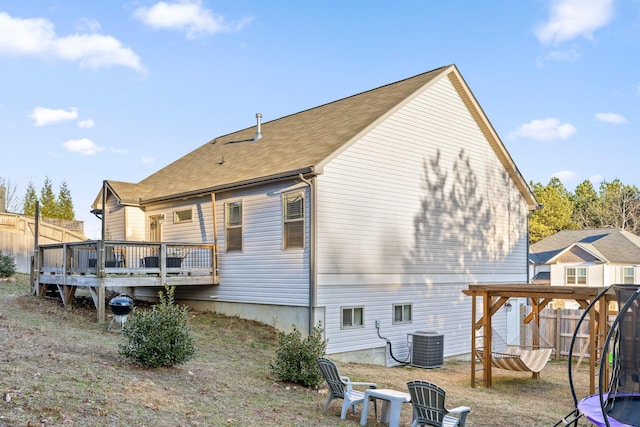 rear view of property featuring central air condition unit, a trampoline, and a wooden deck