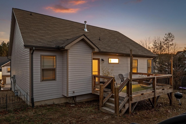 back house at dusk with a wooden deck and a trampoline