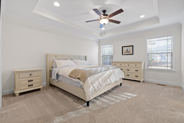 bedroom featuring multiple windows, a tray ceiling, ceiling fan, and light colored carpet