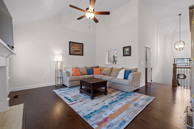 living room with ceiling fan with notable chandelier, dark hardwood / wood-style flooring, and high vaulted ceiling