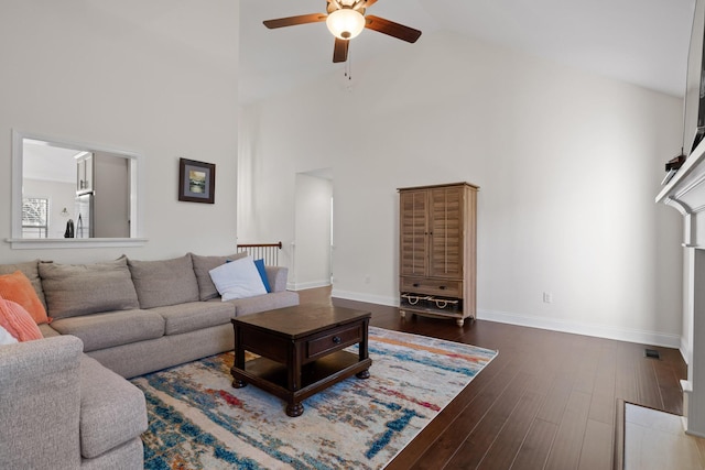 living room featuring a high ceiling, ceiling fan, and wood-type flooring