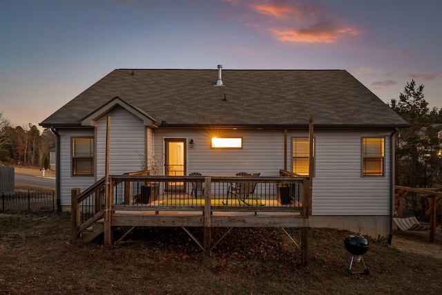 back house at dusk featuring a wooden deck