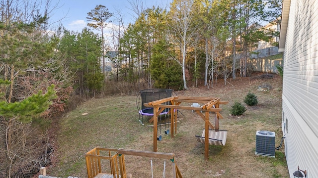 view of yard with a trampoline and central AC