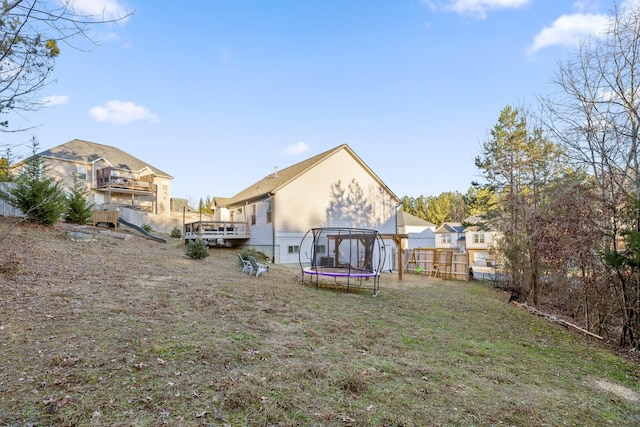 rear view of house with a trampoline and a deck