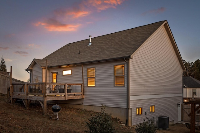 back house at dusk with central AC and a wooden deck