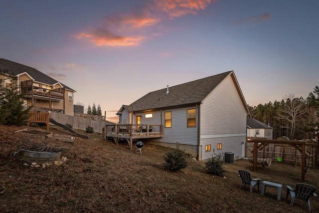 back house at dusk featuring cooling unit and a wooden deck