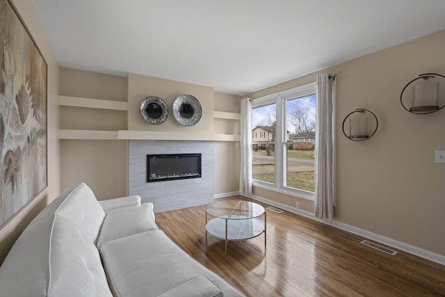 living room featuring hardwood / wood-style flooring, built in shelves, and a fireplace