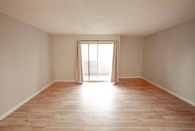 empty room featuring light wood-type flooring and a textured ceiling