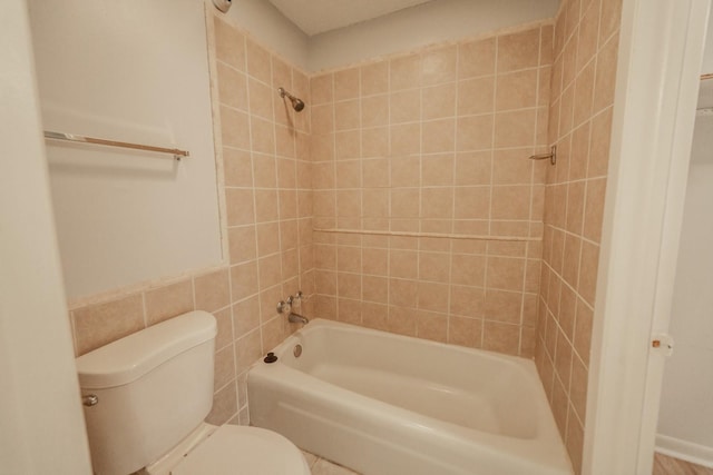 bathroom with toilet and tiled shower / bath