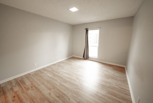 unfurnished room with a textured ceiling and light hardwood / wood-style flooring