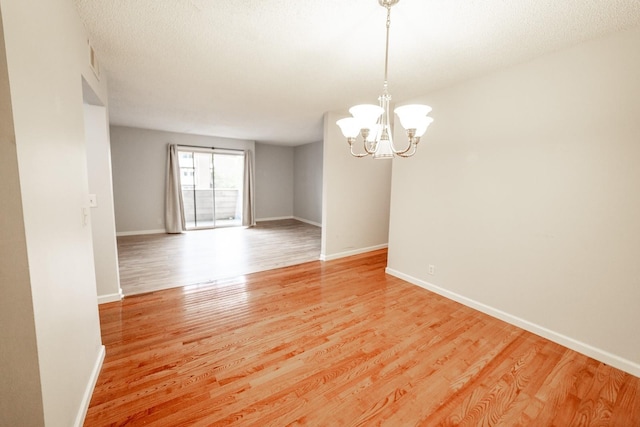 unfurnished room with wood-type flooring and an inviting chandelier