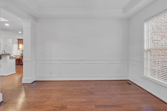 empty room featuring hardwood / wood-style floors, a raised ceiling, and ornamental molding