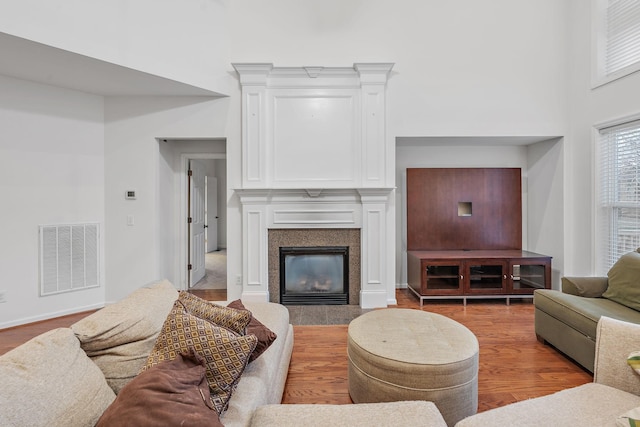 living room featuring hardwood / wood-style floors, a high ceiling, and a tile fireplace