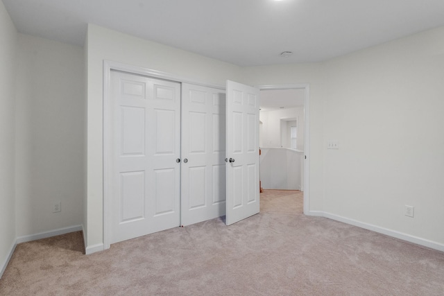 unfurnished bedroom featuring light carpet and a closet