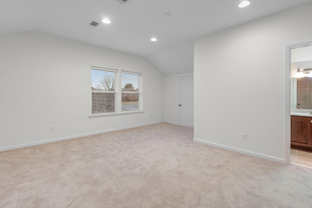 additional living space featuring light colored carpet and vaulted ceiling