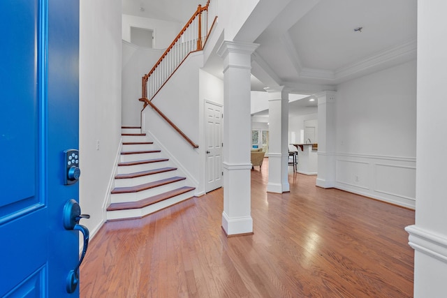 foyer with ornamental molding, a tray ceiling, and light hardwood / wood-style floors