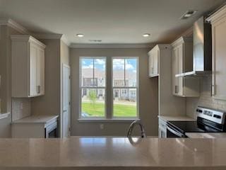 kitchen featuring white cabinets, ornamental molding, stainless steel electric range oven, and wall chimney exhaust hood