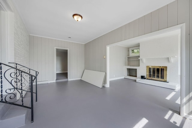 unfurnished living room featuring baseboard heating, wooden walls, a fireplace, and ornamental molding