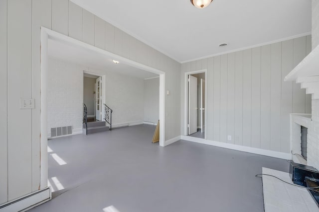 unfurnished living room with baseboard heating, a fireplace, wooden walls, and concrete floors