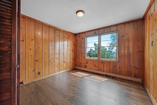 empty room featuring wooden walls, a baseboard radiator, dark hardwood / wood-style floors, and ornamental molding