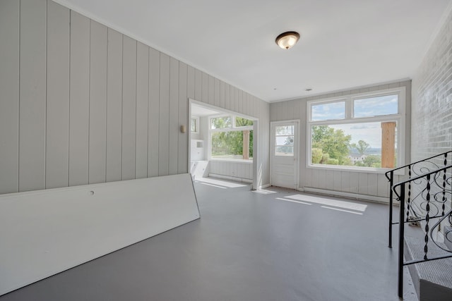 unfurnished living room featuring a baseboard heating unit, concrete floors, and wooden walls