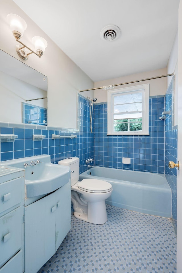 full bathroom with vanity, tiled shower / bath combo, tile walls, and toilet