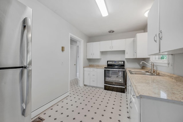 kitchen with stainless steel fridge, white cabinetry, sink, and black electric range