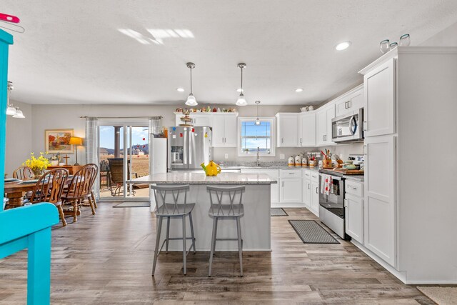 kitchen with sink, white cabinetry, a kitchen island, pendant lighting, and stainless steel appliances