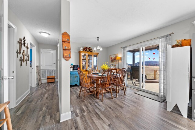 dining space with dark hardwood / wood-style flooring, a textured ceiling, and a notable chandelier