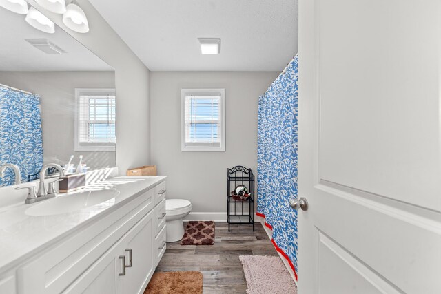 bathroom featuring vanity, hardwood / wood-style flooring, plenty of natural light, and toilet