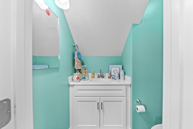 bathroom with vanity, lofted ceiling, and a textured ceiling