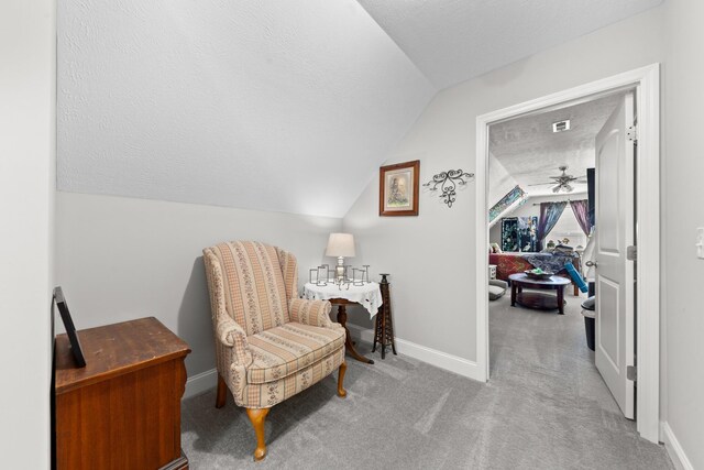 living area featuring light carpet, vaulted ceiling, and a textured ceiling