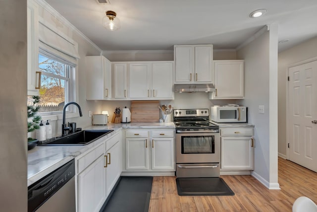 kitchen with light stone countertops, appliances with stainless steel finishes, white cabinetry, light hardwood / wood-style floors, and sink