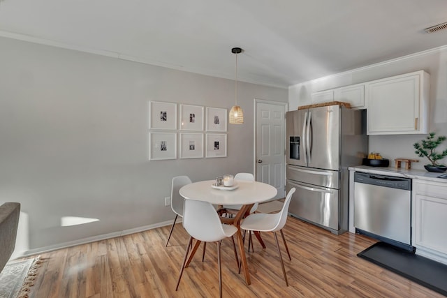 dining space with light wood-type flooring and crown molding