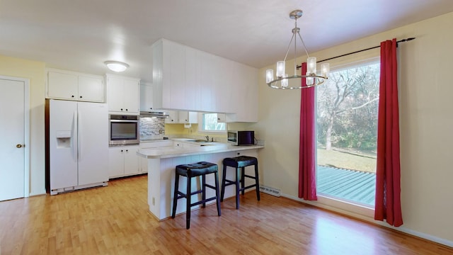 kitchen featuring hanging light fixtures, stainless steel appliances, an inviting chandelier, kitchen peninsula, and white cabinets