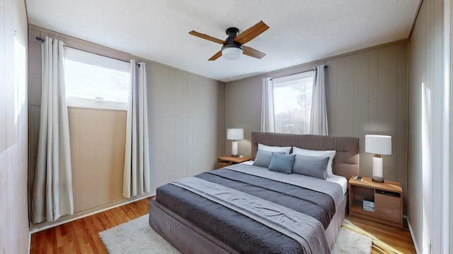 bedroom with ceiling fan, light hardwood / wood-style flooring, and a textured ceiling