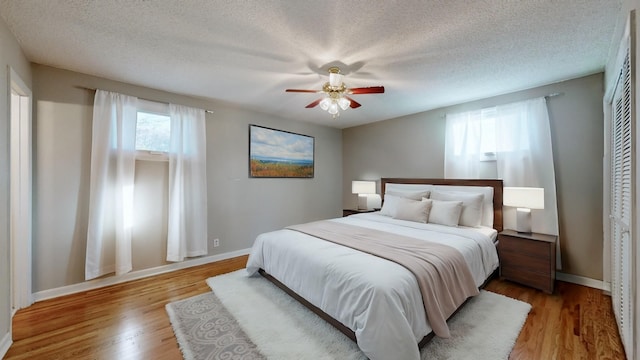 bedroom with ceiling fan, a closet, a textured ceiling, and light wood-type flooring