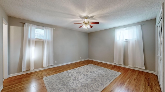 spare room with a textured ceiling, light hardwood / wood-style floors, and ceiling fan