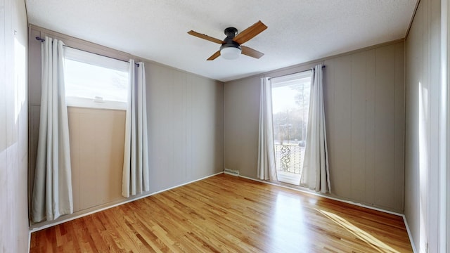 spare room featuring ceiling fan, light hardwood / wood-style flooring, and a textured ceiling