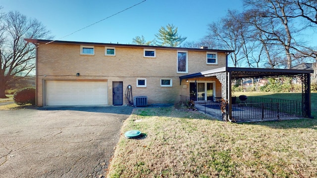 back of property featuring a yard, a garage, and central air condition unit