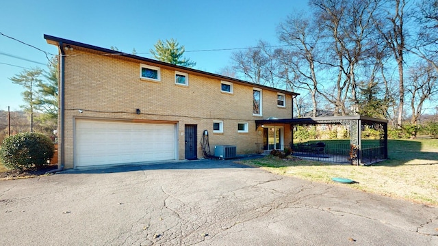 back of house with central air condition unit and a garage