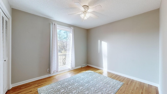 empty room with ceiling fan, light hardwood / wood-style floors, and a textured ceiling