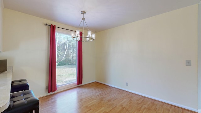 unfurnished dining area with light hardwood / wood-style flooring, an inviting chandelier, and a wealth of natural light