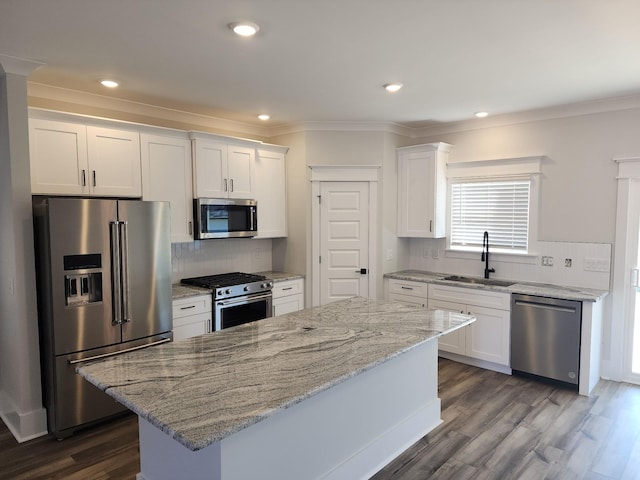 kitchen with white cabinets, a center island, stainless steel appliances, and sink