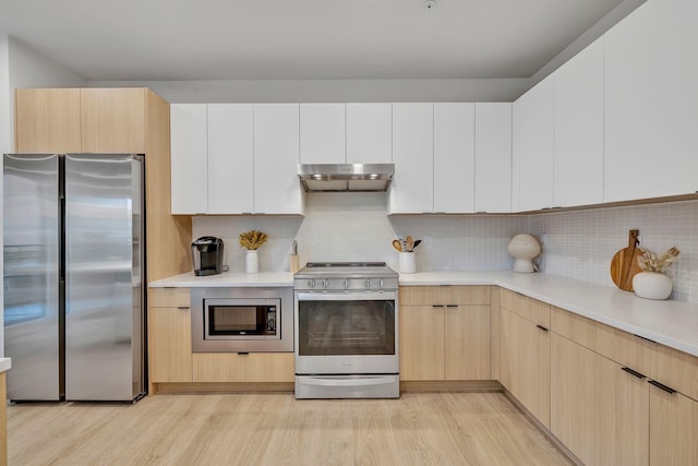 kitchen featuring light brown cabinetry, light wood-type flooring, backsplash, and appliances with stainless steel finishes