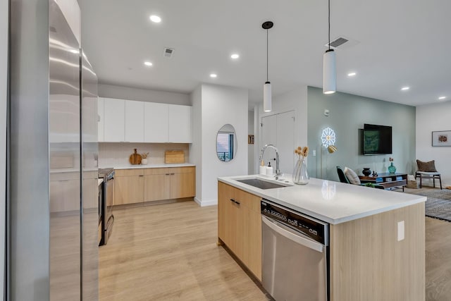 kitchen featuring white cabinets, a center island with sink, sink, light hardwood / wood-style flooring, and stainless steel appliances