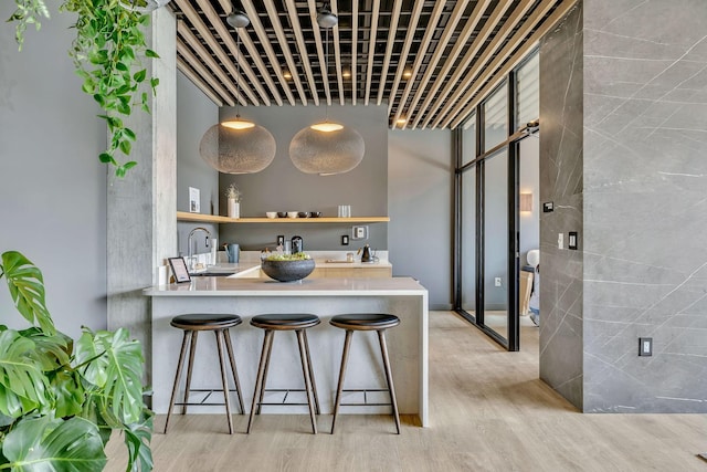 kitchen with a kitchen breakfast bar, light hardwood / wood-style floors, kitchen peninsula, and sink