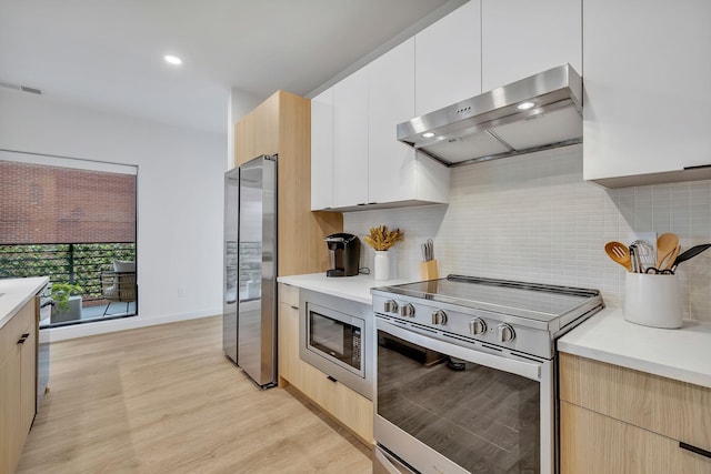 kitchen with ventilation hood, light wood-type flooring, backsplash, and appliances with stainless steel finishes